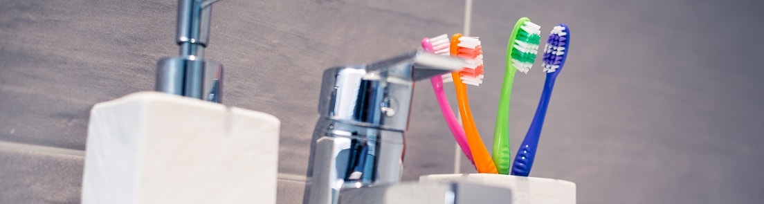 toothbrushes next to bathroom tap